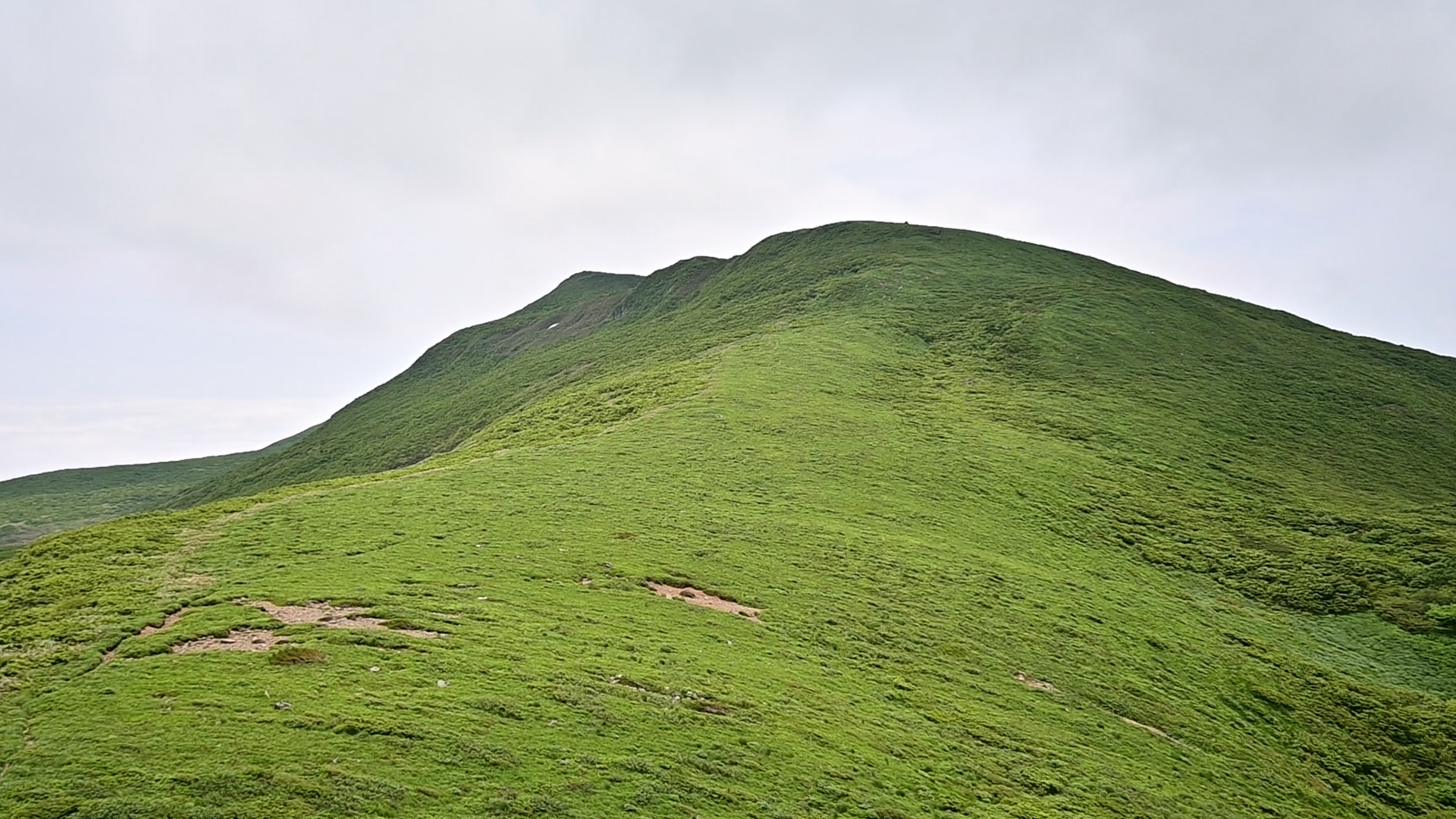 The summit, much like others in heavy snow regions, isn't overly steep but rather a gently undulating landscape of hills, featuring serene marshes and expansive flower fields that form the headwaters of the valleys you've just traversed. 02